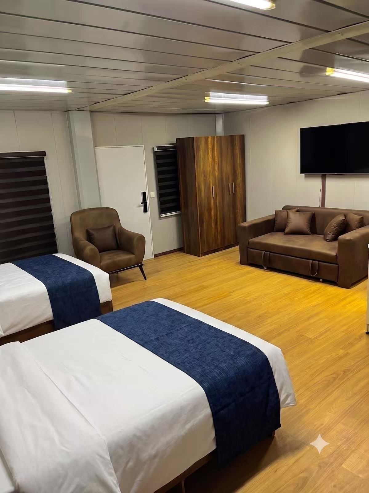 Twin guest room with wardrobe, TV and lounge seating