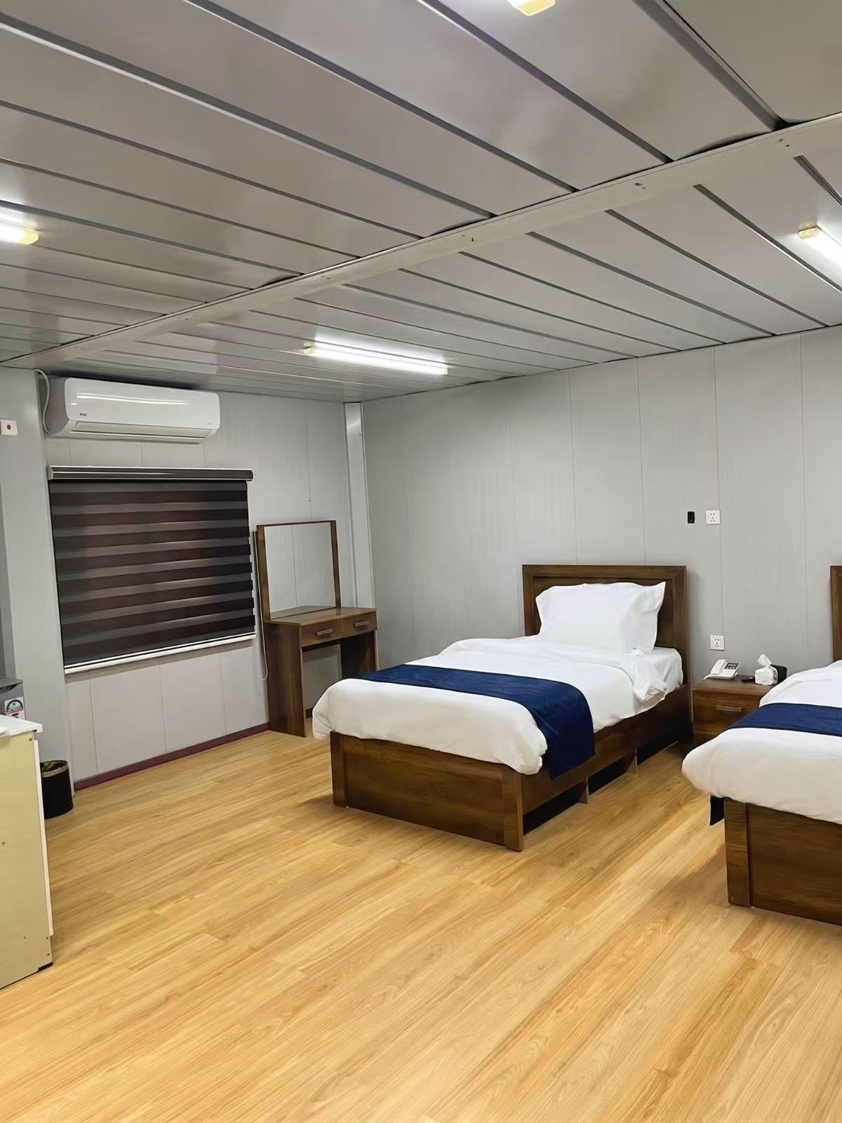 Guest room with twin beds, dresser and wall-mounted A/C